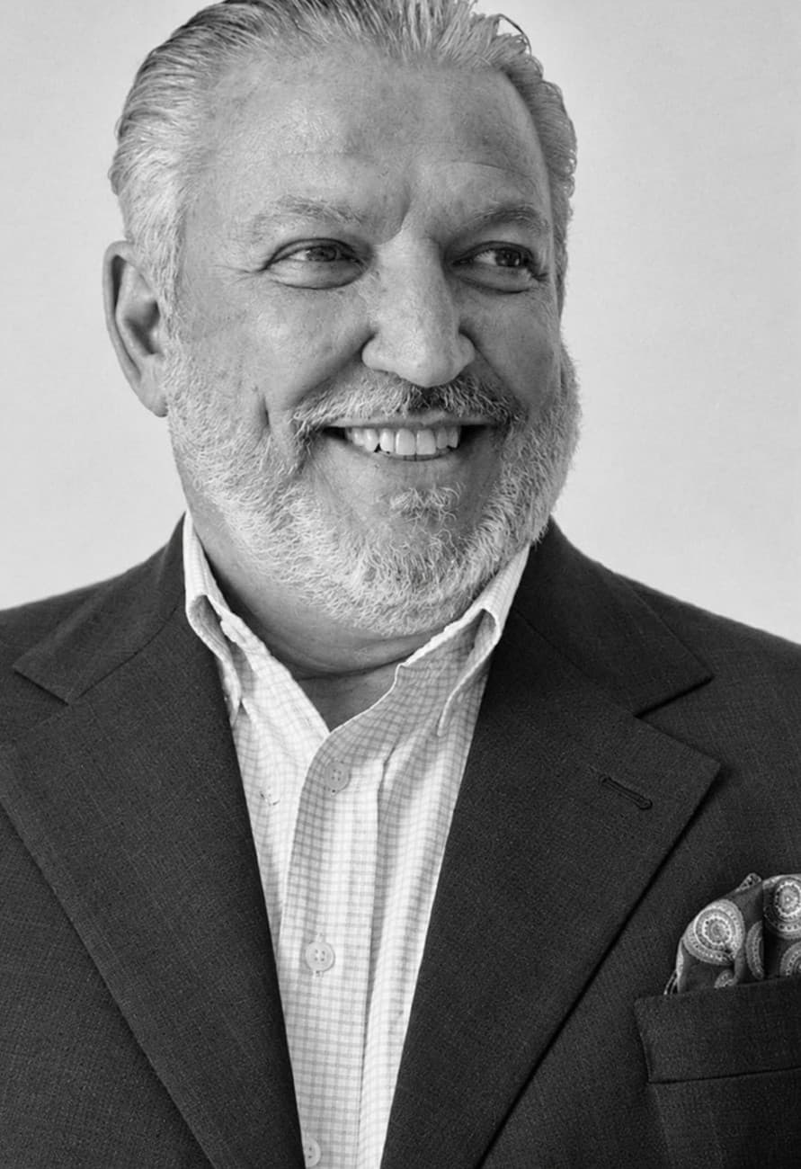 Retrato em preto e branco de Francisco Britto, sorrindo, de paletó escuro e camisa quadriculada